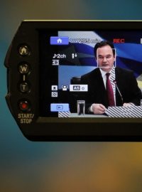 Řecký ministr financí Georgie Papaconstantinou v monitoru kamery na tiskové konferenci, na níž slibuje zmírnění splátek