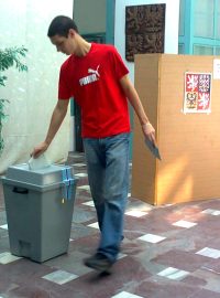 Volič vhazuje svůj lístek do urny ve volební místnosti na radnici v Krupce.