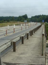 Chodníček na kraji mostu přes dálnici D3 na jednom konci končí v poli a na druhém prochází okružní křižovatku