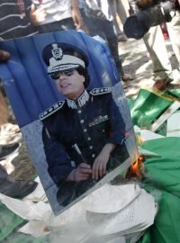 Demonstranti pálí plakáty Kaddáfího.