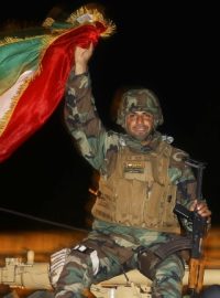 Bojovník kurdských milic pešmerga na vojenském voze mířícím do Kobani
