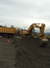 Dělníci odtěžují zeminu z horní části sesuvu nad rozestavěnou dálnicí
