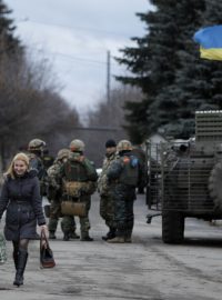 Obyvatelky vesnice Debalceve v Doněcké oblasti míjejí skupinu ukrajinských vojáků