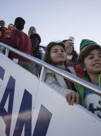 Třicítka uprchlíků ze Sýrie a Iráku nastupuje do letadla na letišti v Aténách