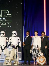 Star Wars. Zleva bílí vojáci Impéria, takzvaní stormtroopeři, herci  John Boyega a Daisy Ridleyová, režisér J. J. Abrams a herec Adam Driver. V popředí vlevo robot R2-D2 a vpravo nový BB-8