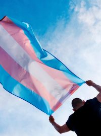 Osoba držící vlajku hrdosti trans lidí