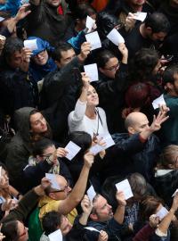 Lidé v Barceloně stojí před hlasovací místností a mávají svými volebními lístky