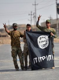 Šíitští milicionáři s vlajkou Islámského státu oslavují vítězství nad extremisty.