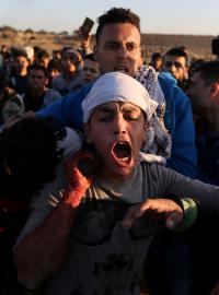 Zraněný palestinský protestující po střetech demonstrantů s Izraelskými jednotkami v pásmu Gazy