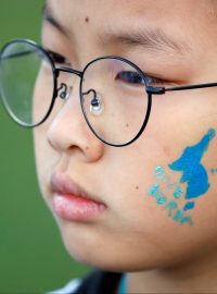 &quot;Jedna Korea&quot;. Modrá silueta Korejského poloostrova (užitá také ve společné korejské vlajce) na tváři jihokorejské dívky během demonstrace za úspěšný průběh mezikorejského summitu. Centrum Soulu, 21. dubna 2018.