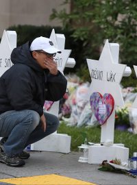 Muž klečící u pomníků obětí střelby v Pittsburghu.