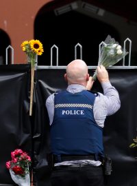 Policista pokládá květiny ke vstupu do mešity v Christchurch