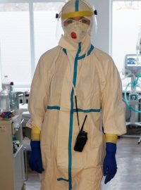 Lékař v ochranném obleku prochází mezi pacienty s nemocí covid-19 v kyjevské nemocnici