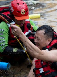 Záchranáři pomáhají muži po vydatných deštích ve vesnici She v provincii Fu-ťien v jihovýchodní Číně
