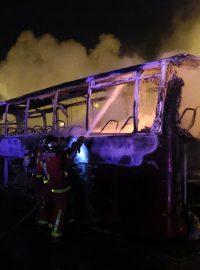Hasiči stříkají vodu na vyhořelý autobus v Nanterre