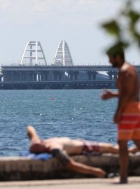 Lidé se opalují a skáčou do vody v blízkosti Krymského mostu, jehož část byla poškozena útokem