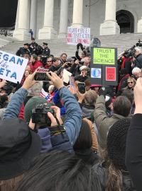 Na konec hodinové akce se demonstranti přesouvají na schody Kapitolu, kde se nechají zatknout