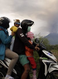 Rodina prchající na skútru kvůli soptícímu vulkánu Agung na Bali
