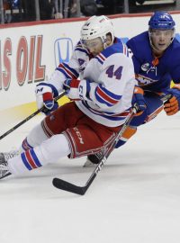 Neal Pionk hrající za New York Rangers si kryje puk před Anthony Beauvillierem z Islanders