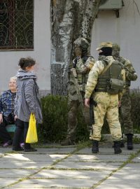 Místní obyvatelé se baví se skupinou ruských vojáků v Chersonu (foto z 20. května, pořízené během cesty organizované ruským ministerstvem obrany)