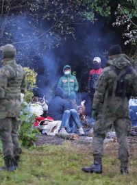 Polští pohraničníci hlídají skupinu migrantů, kteří se pokusili překročit hranici mezi Běloruskem a Polskem poblíž vesnice Usnarz Gorny v Polsku