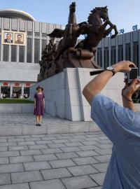 Turisti se fotí v Pchjongjangu před Palácem školáků Mangjongde, 26. července 2018.