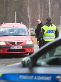 Policista hovoří s řidičem osobního vozu při příjezdu k policejní uzavírce na silnici do Poličky